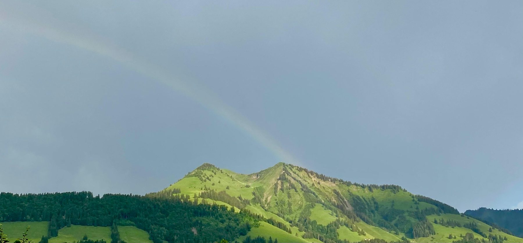 Un arc-en-ciel discret se pose sur l'alpage après la pluie — photographié par Nadiejda