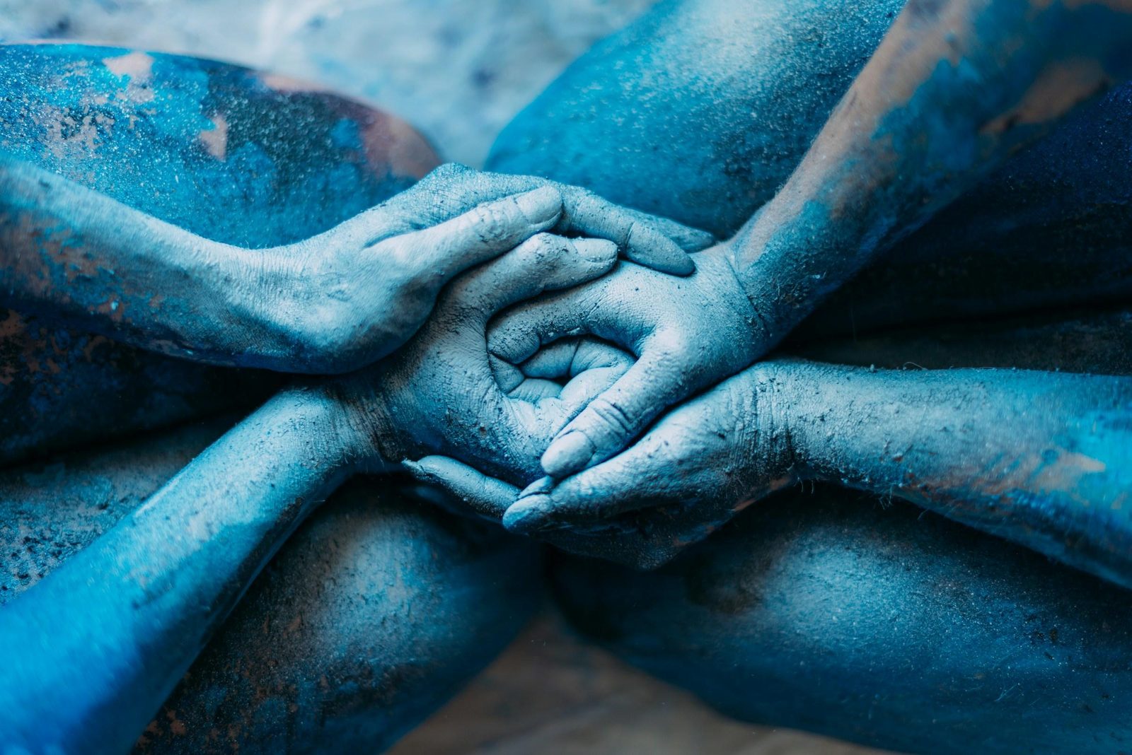 Des mains de femmes entrelacées, poudrées de pigment bleu — le cercle, le rituel, la sororité